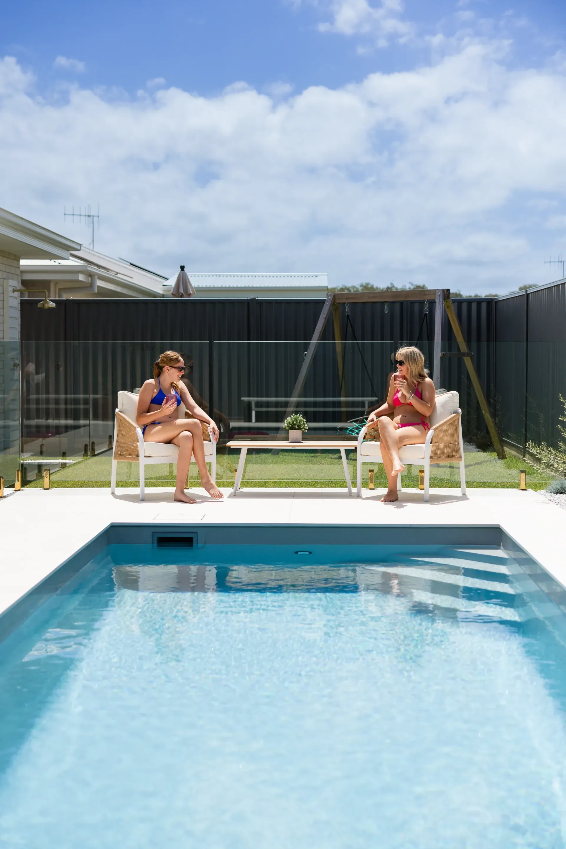 Two People Lounging by A Backyard Pool on Chairs Under a Sunny Sky — New Vision Pools in Port Macquarie, NSW
