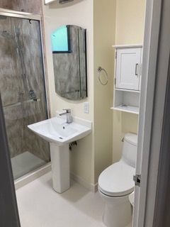 Modern bathroom with gray tile, white vanity, and glass shower enclosure