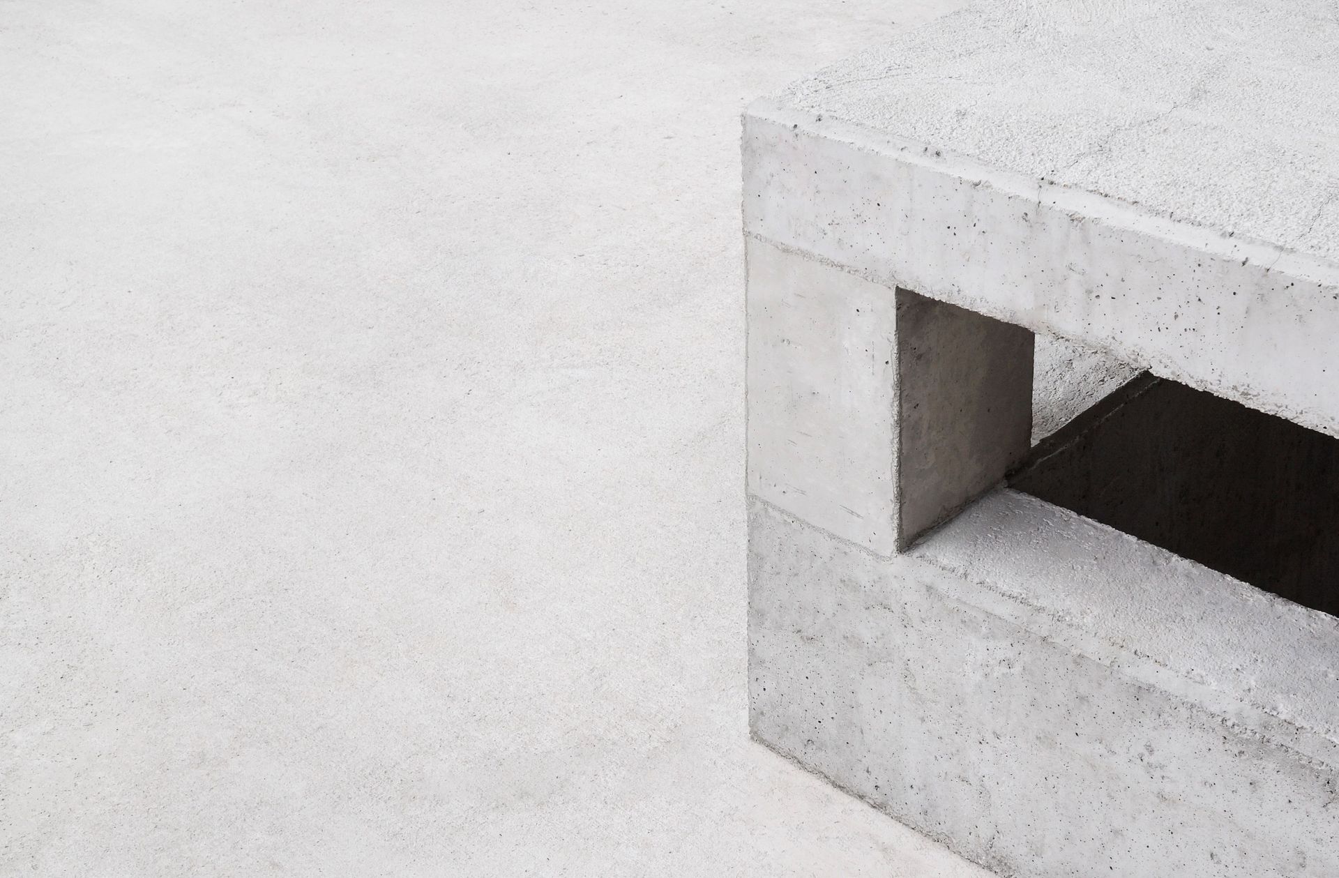 Minimalist white concrete bench with a rectangular cutout on a pale background