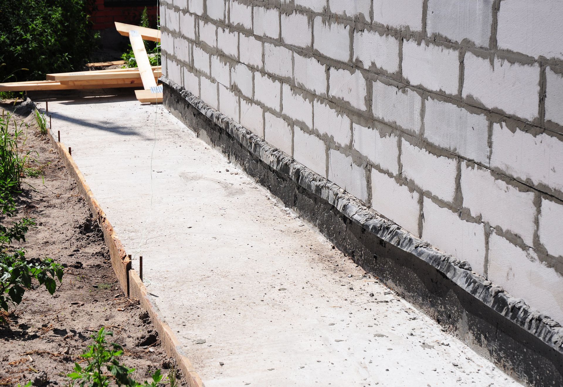 A brick wall with a concrete walkway in front of it