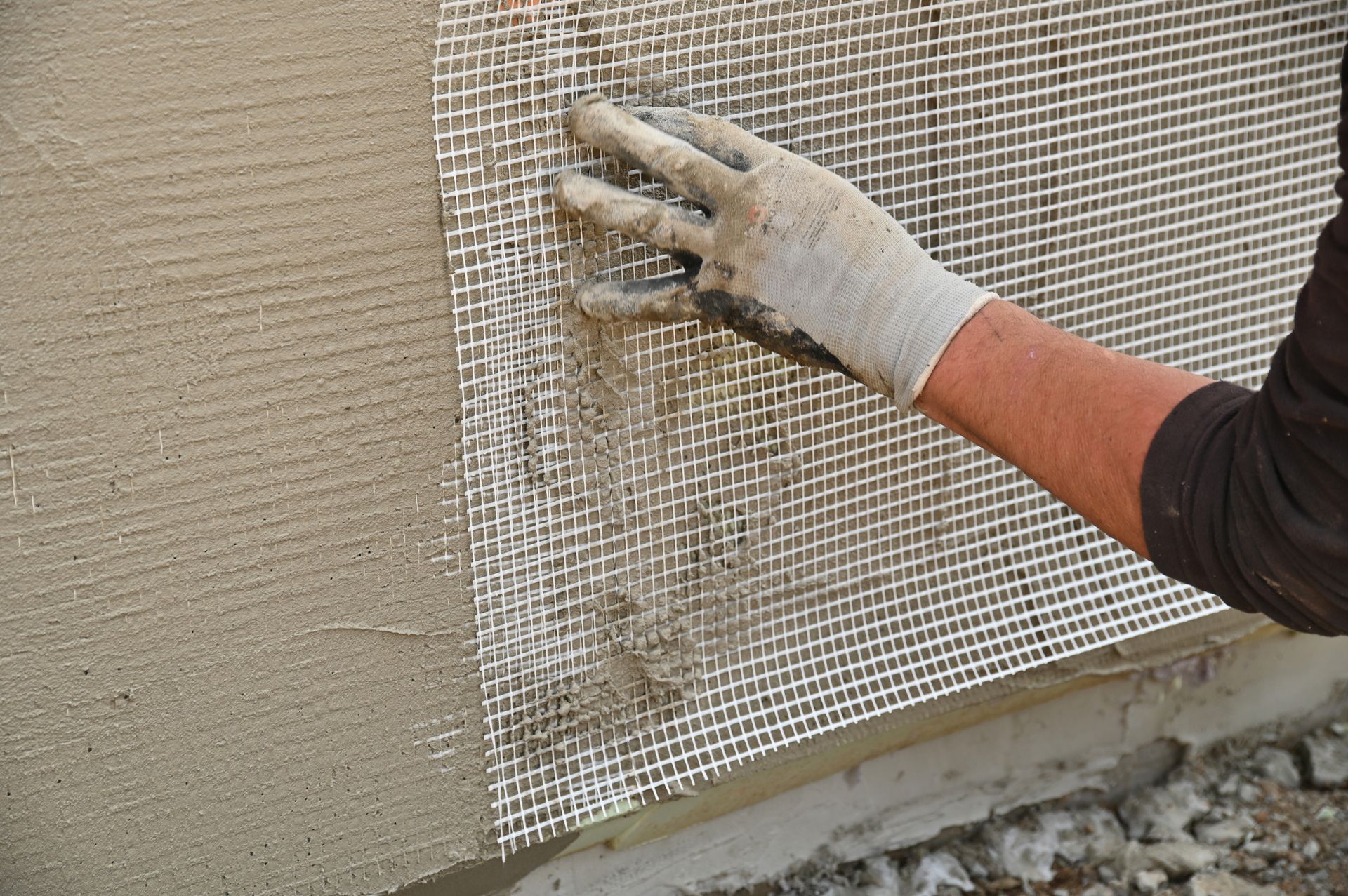 A person wearing gloves is working on a wall.