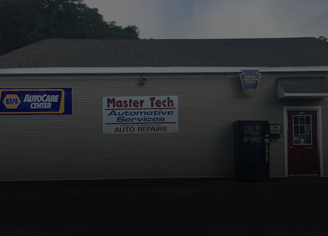 Auto repair shop exterior with Master Tech and NAPA AutoCare Center signs on beige siding.