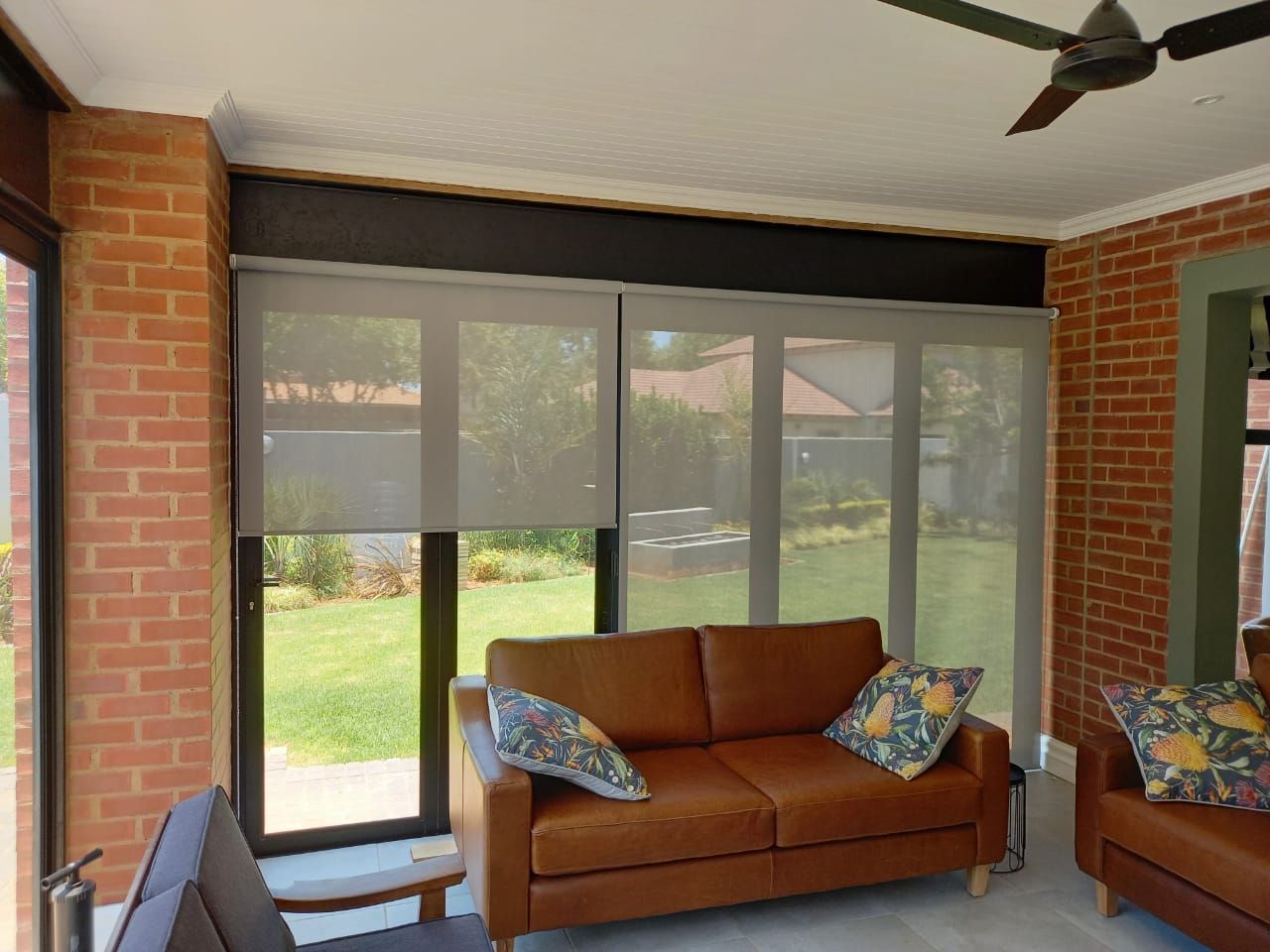 A living room with a brown couch and a ceiling fan