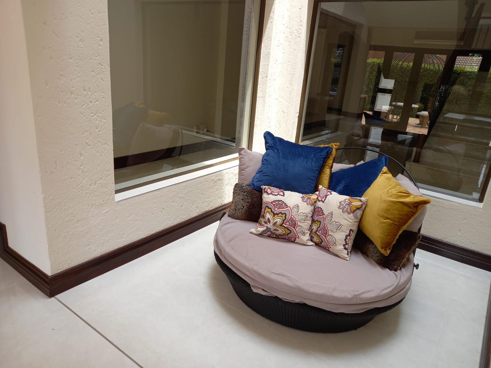 A round couch with blue and yellow pillows on it