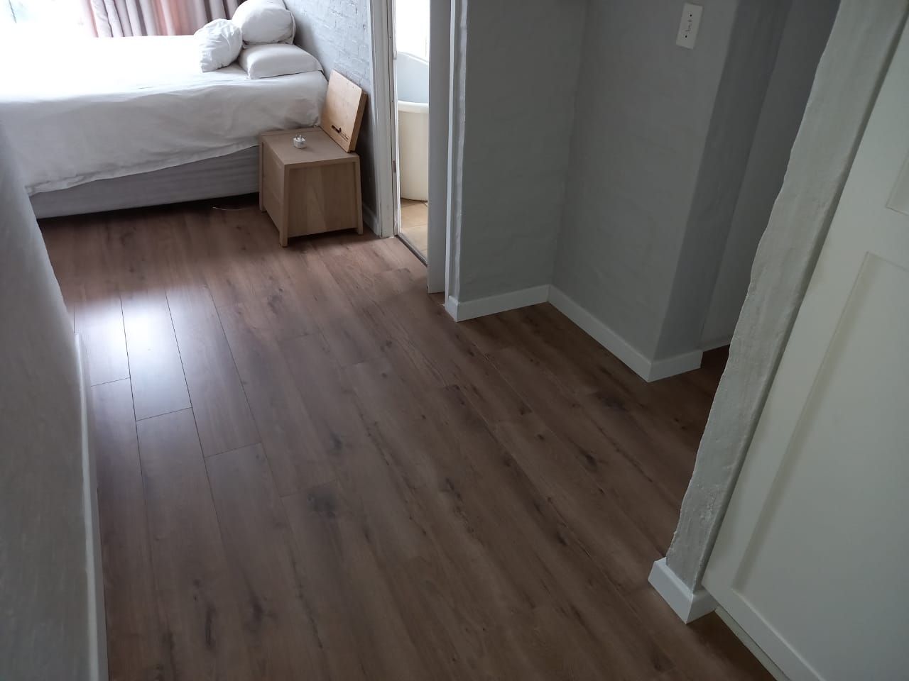 A bedroom with a wooden floor and a bed