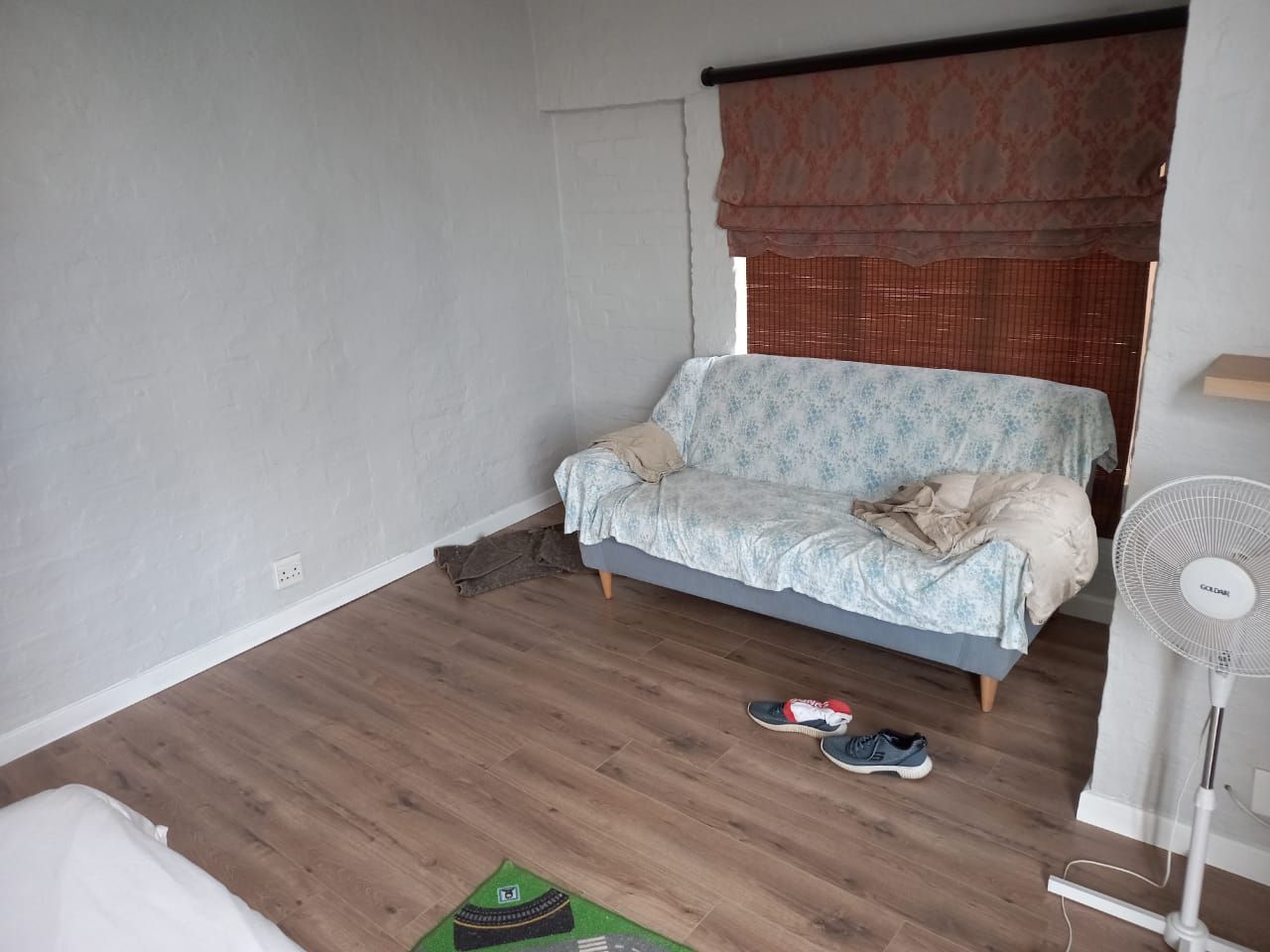 A living room with a couch and a fan.