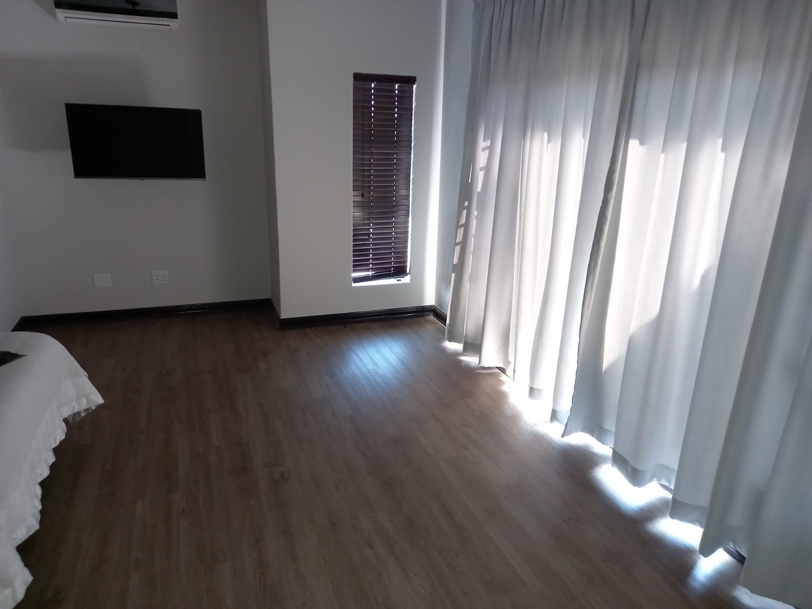 A bedroom with a bed , television , and sliding glass doors.