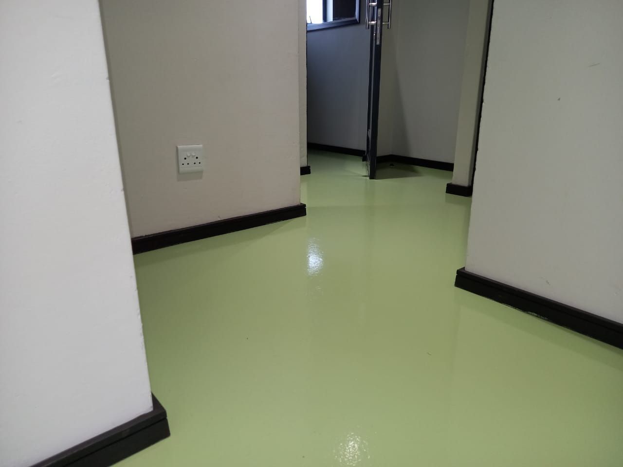 A hallway with a green floor and a door.
