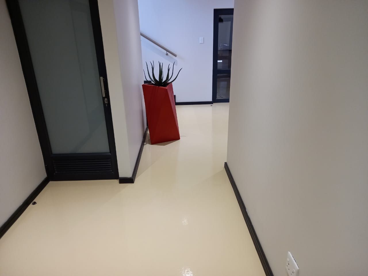 A hallway with a red potted plant in the middle