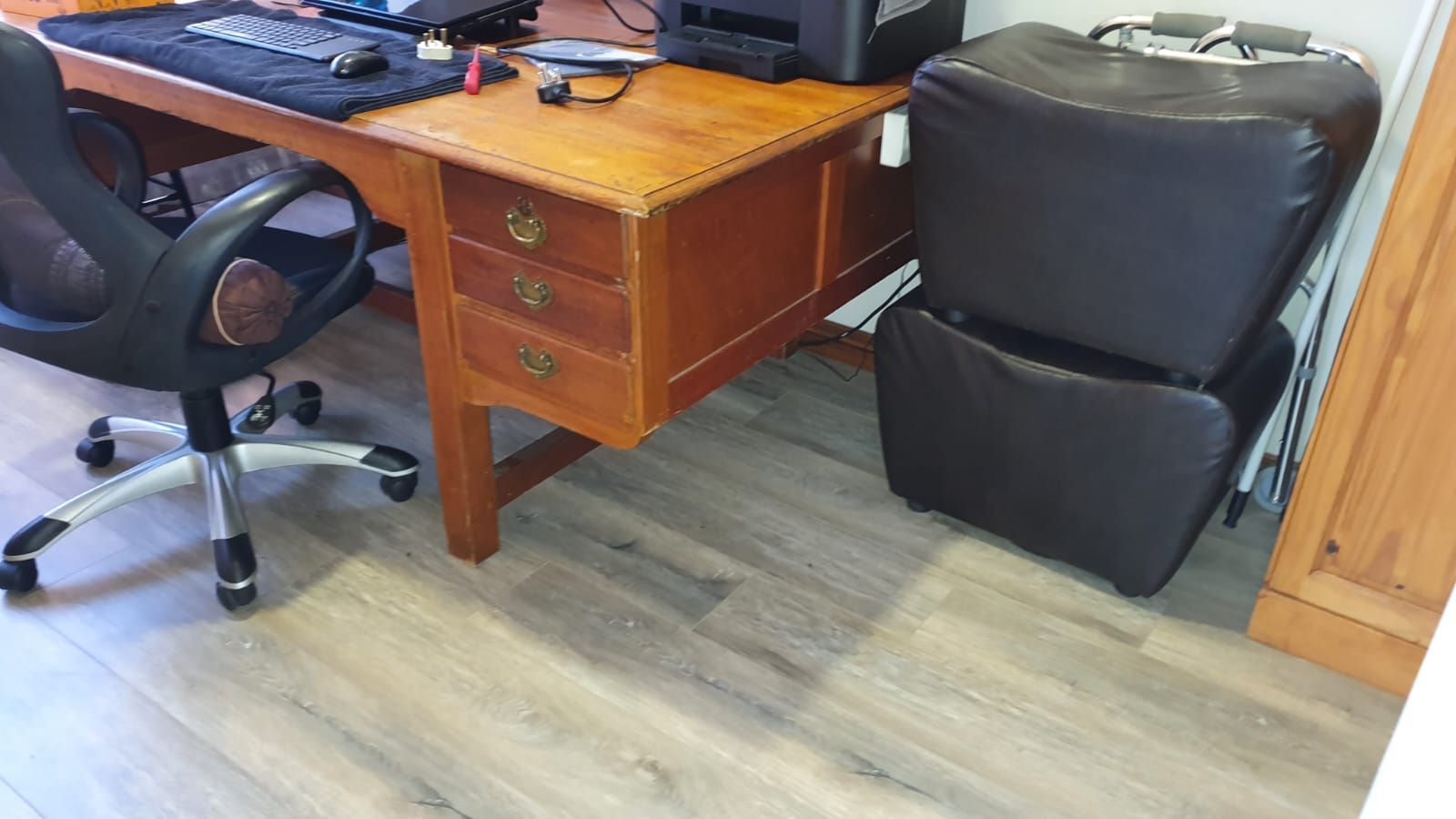 A wooden desk with a black chair and a printer on it.