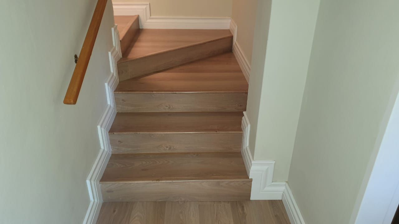 A wooden staircase with a wooden railing in a hallway.