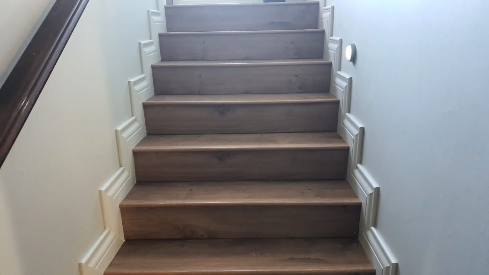 A set of wooden stairs leading up to a white wall