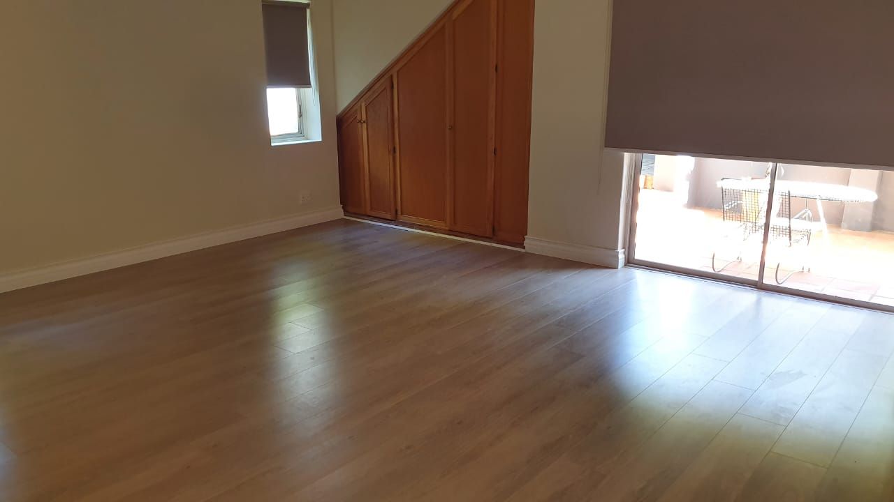 An empty room with hardwood floors and a sliding glass door.