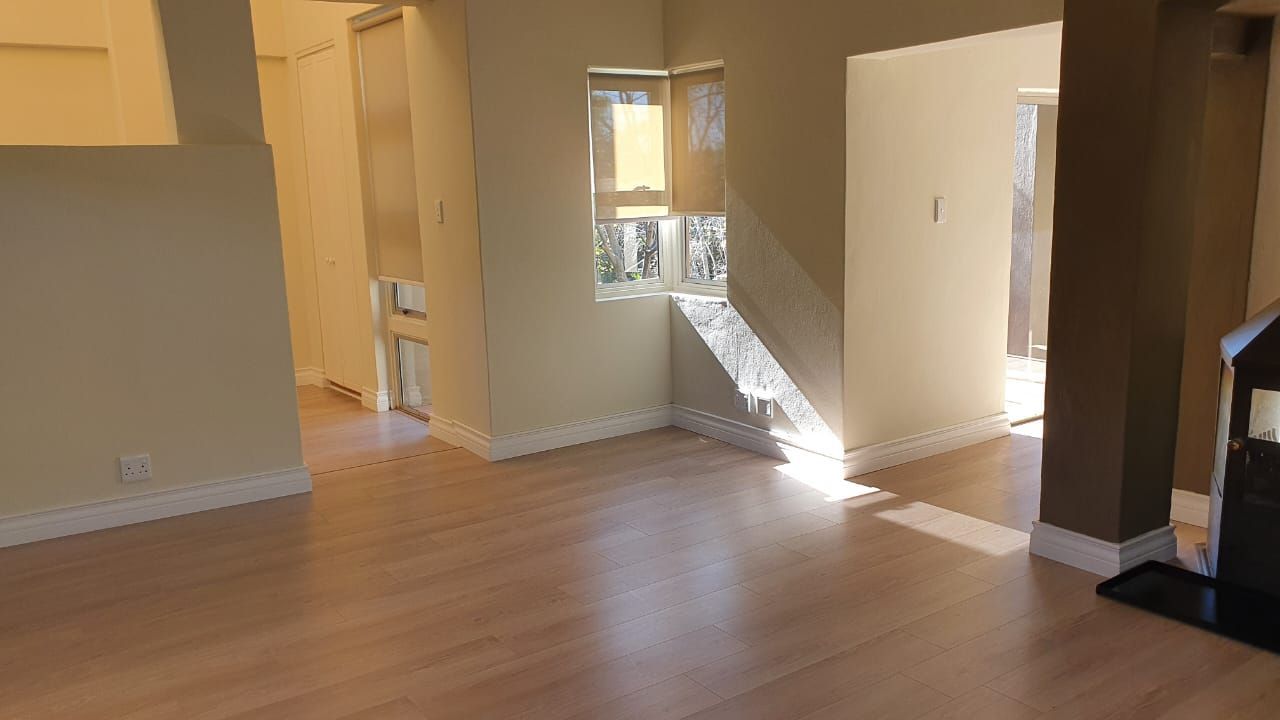 An empty living room with hardwood floors and a fireplace.