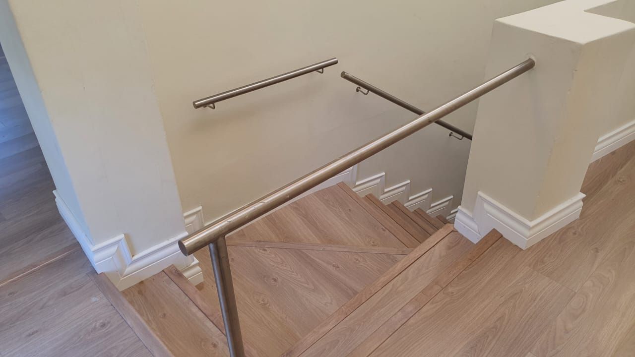A staircase with a stainless steel railing and a wooden floor.