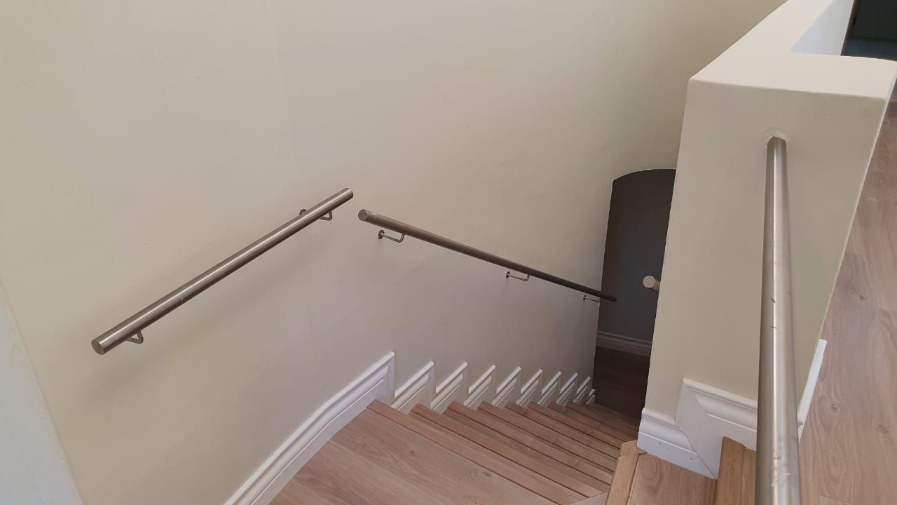 A staircase with a stainless steel railing and wooden steps in a house.