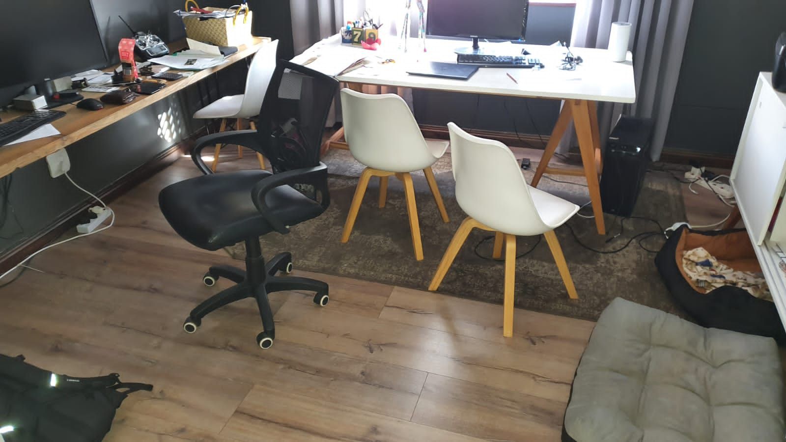 A room with a desk and chairs and a dog on the floor.