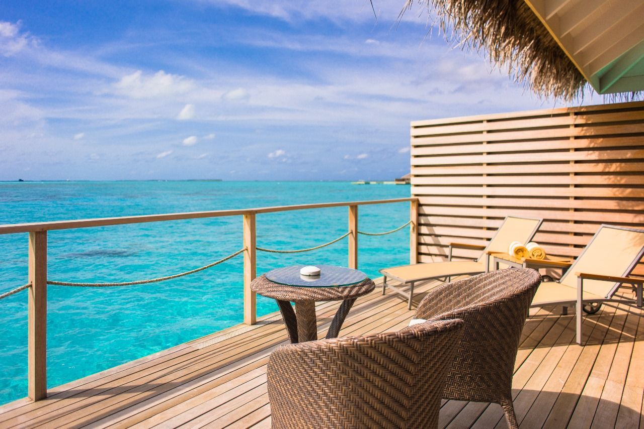 There is a table and chairs on the deck overlooking the ocean.