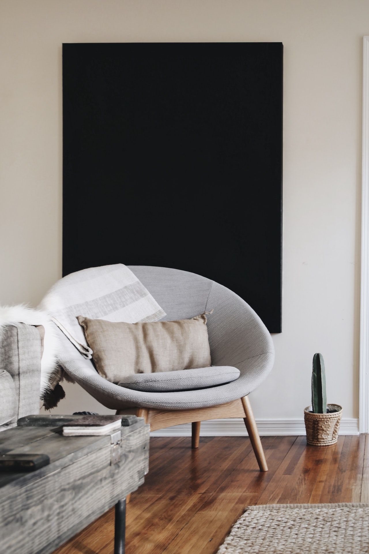 A living room with a chair , couch , coffee table and a potted plant.