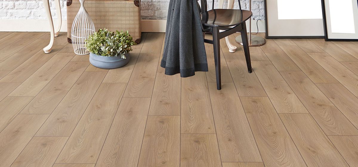 A wooden floor with a chair and a table in a living room.