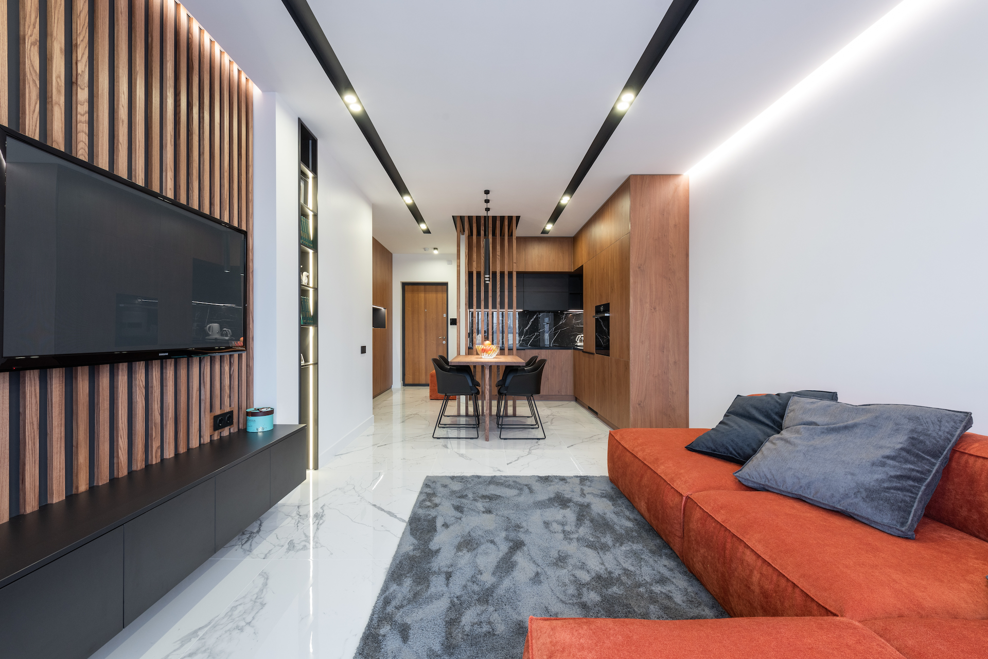 A living room with an orange couch and a flat screen tv.