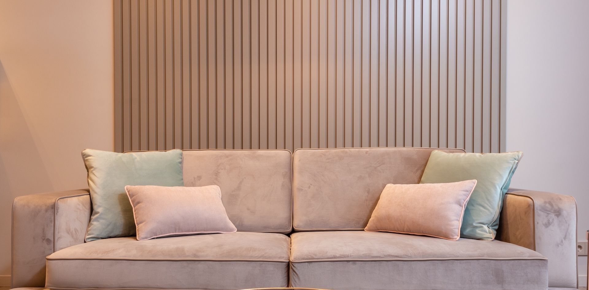 A living room with a couch and pillows in front of a wall.