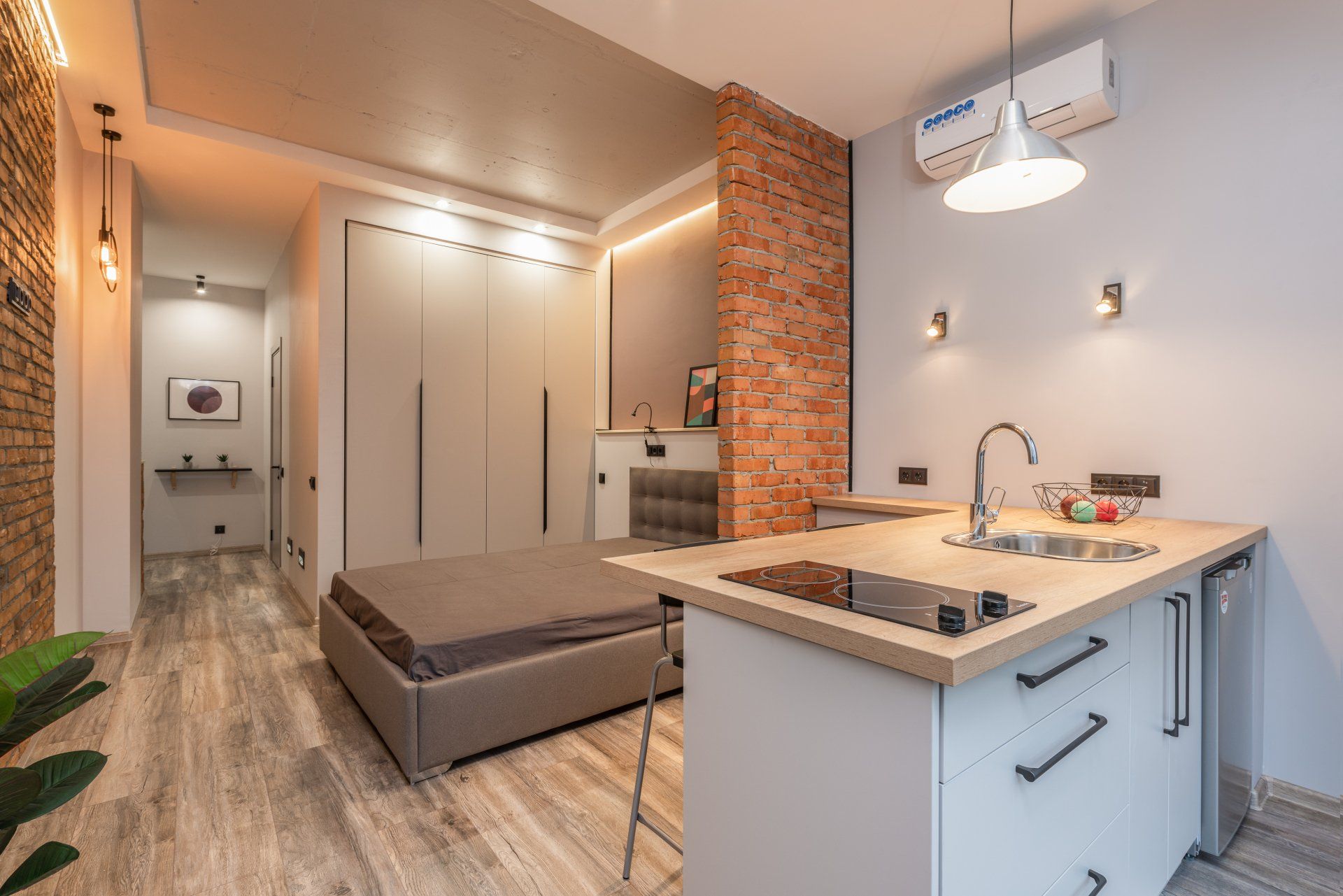 A bedroom with a bed and a kitchen in a small apartment.