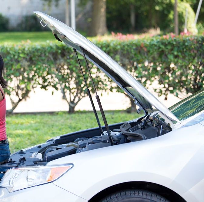 A woman is leaning on the hood of a broken down car — Strut Re-gas Mackay In Ooralea, QLD
