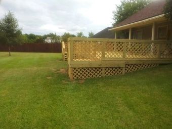 A wooden deck with a lattice fence in front of a house
