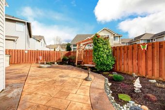 A backyard with a wooden fence and a patio.