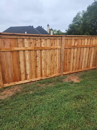 A wooden fence is sitting in the middle of a lush green field.
