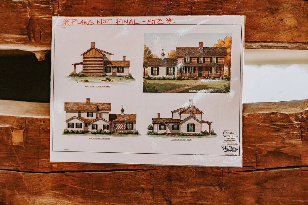 Architectural design sheet with four house elevations pinned on a brick wall