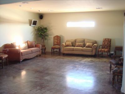 Empty living room with beige sofas, chairs, and a glossy dark floor in soft light