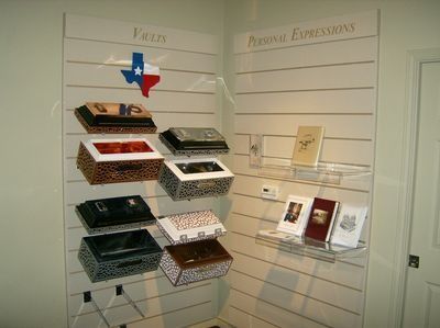 Display of decorative coffin-shaped cases and cards on slatwall shelves in a shop