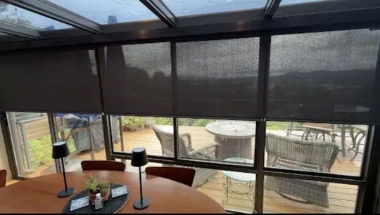 Sunroom dining area with round table, chairs, and large windows overlooking a patio and yard