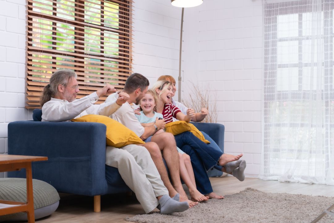 Family sitting on a blue couch, laughing together in a bright living room.