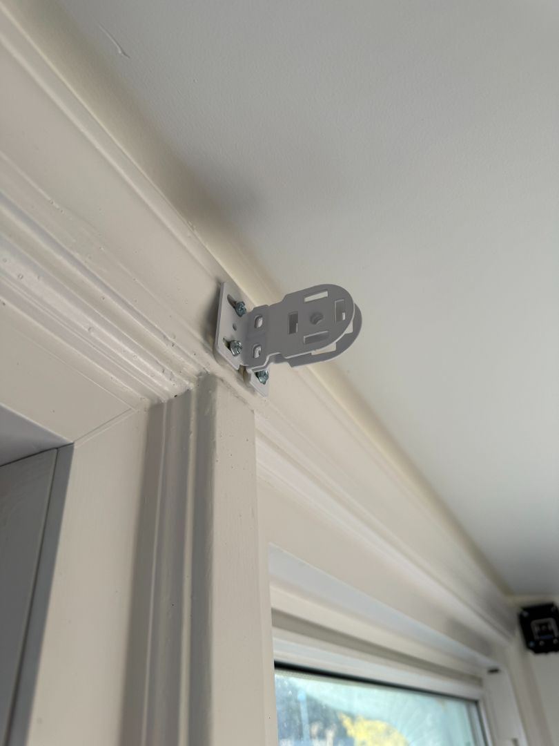 White doorframe with a small gray metal hinge or bracket mounted near the top corner.