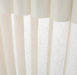 White sheer curtains with a subtle floral pattern hanging in front of a window.