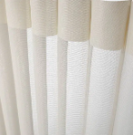 Beige and white textured curtain panels hanging in soft folds