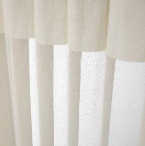 Close-up of cream-colored curtains with soft vertical folds and sheer white panels