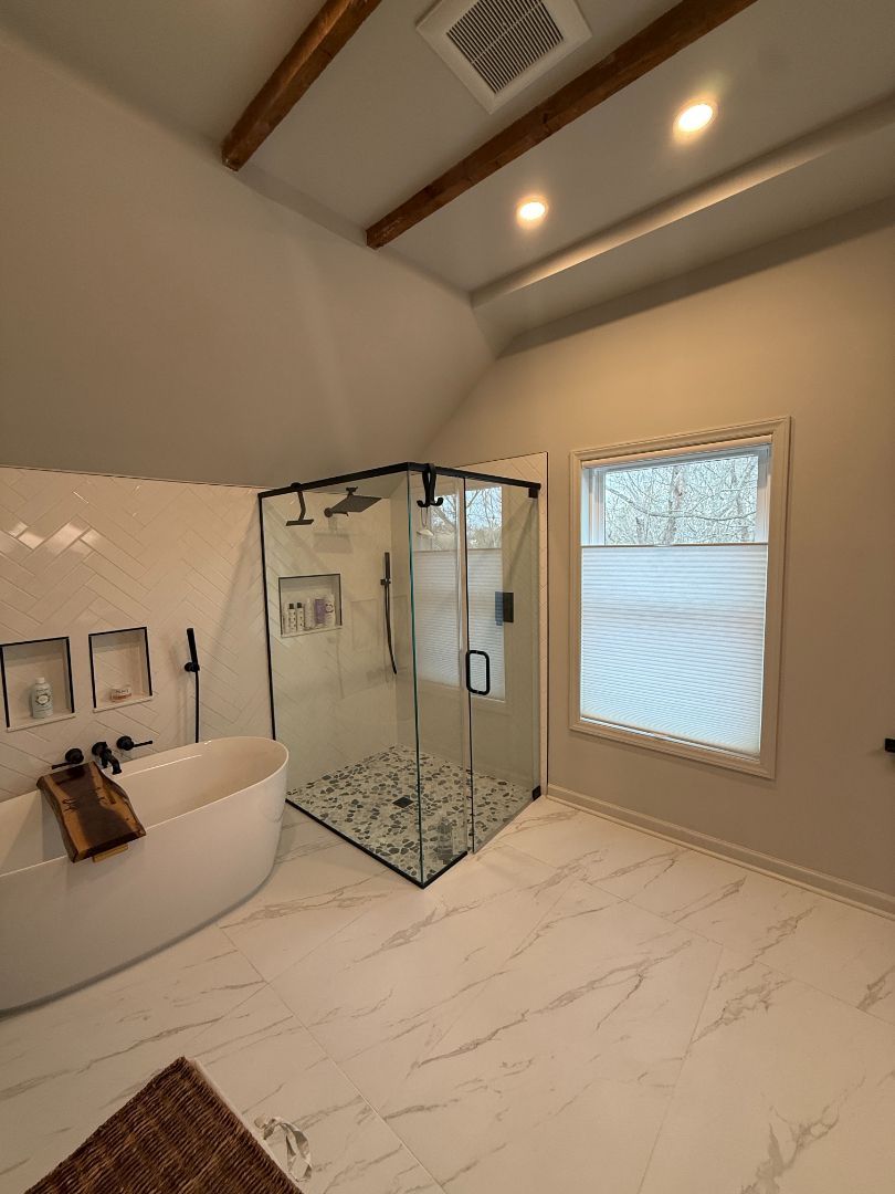 Modern bathroom with glass shower, freestanding tub, and vaulted ceiling with wood beams
