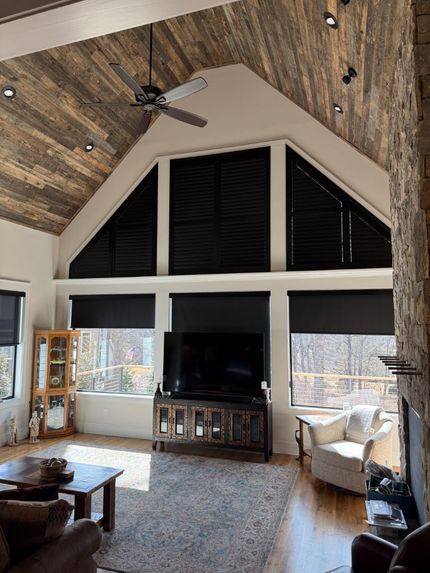 Living room with sectional sofa, window shades, and dining area.