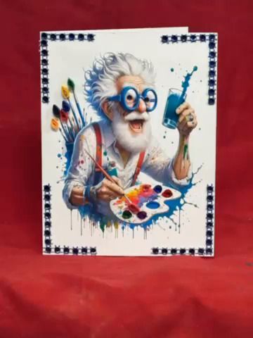 White-bearded painter with blue glasses mixing colorful paint on a canvas, framed by decorative border