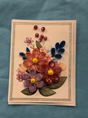 Quilled floral bouquet card with pink, blue, and green paper flowers on cream background