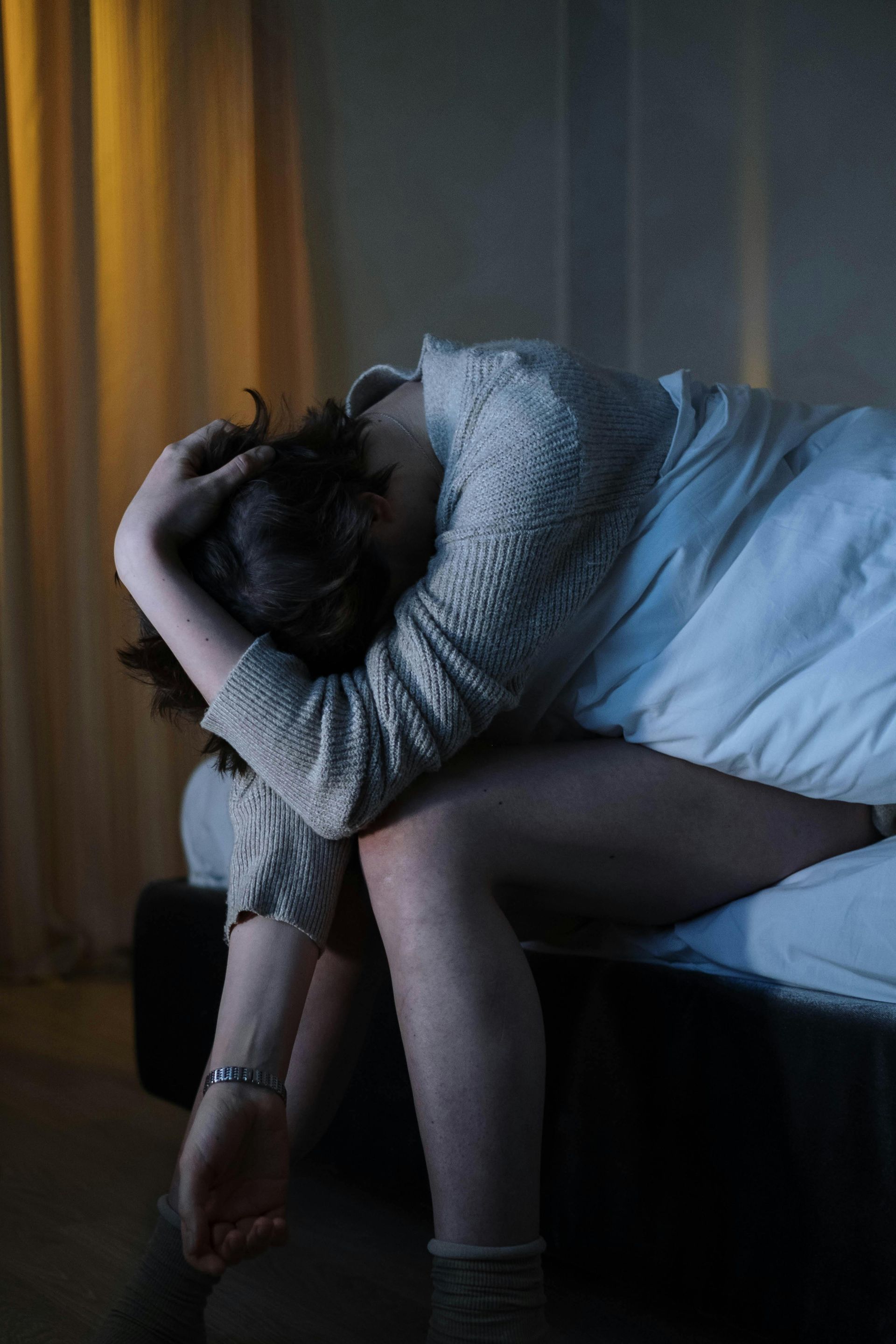 Erschöpfte Frau sitzt gedankenverloren auf dem Bett – Symbolbild für Stress und innere Unruhe