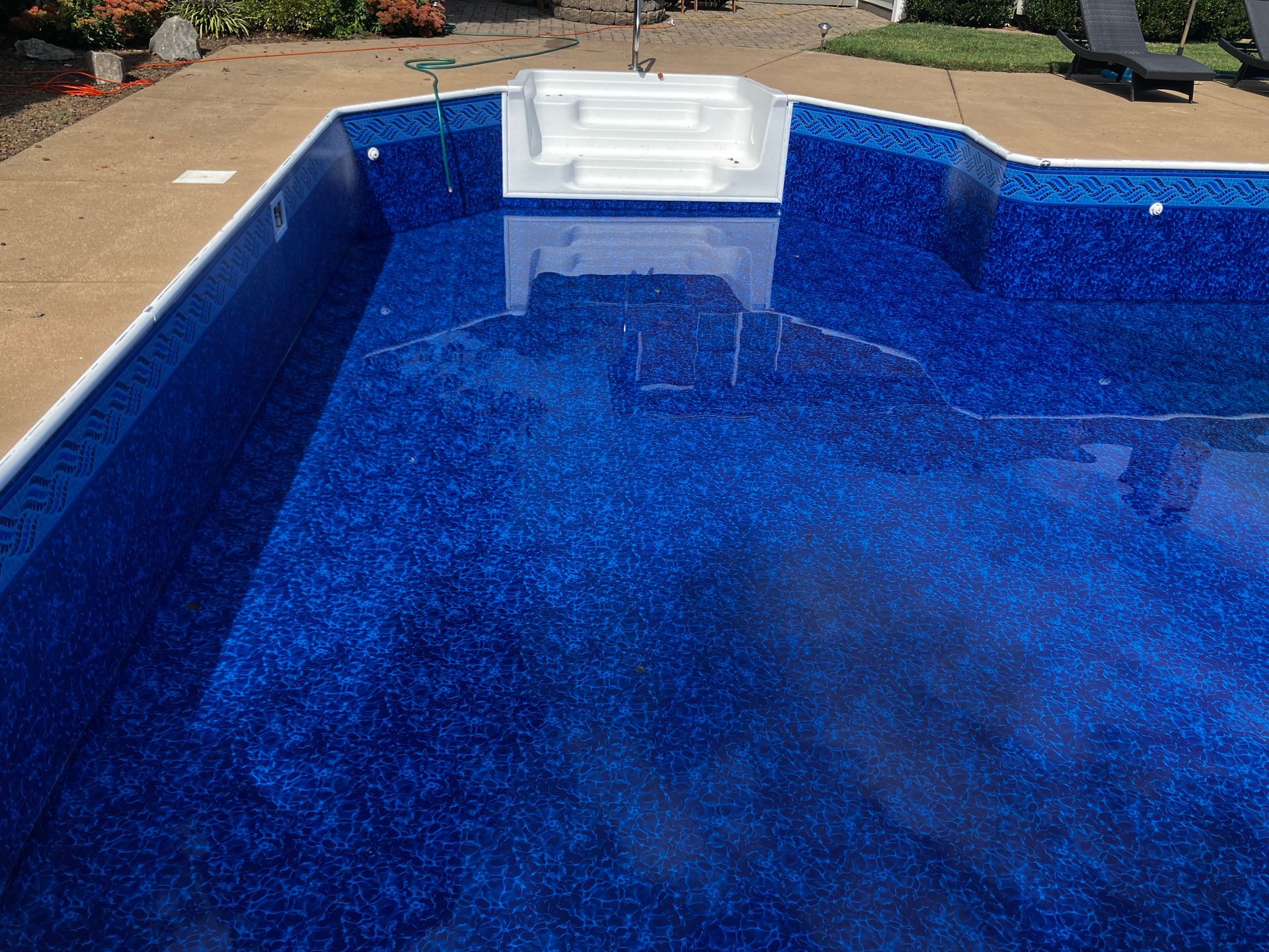 Blue swimming pool with a white bench seat at the shallow end, viewed from above