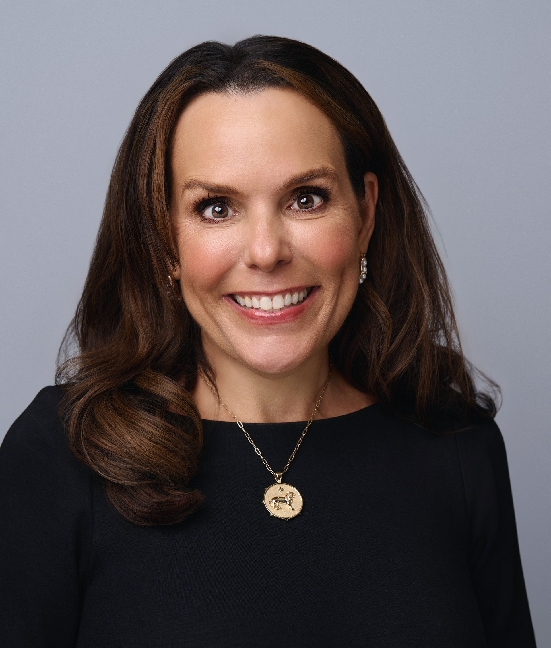 A woman wearing glasses and a blue shirt is smiling for the camera.