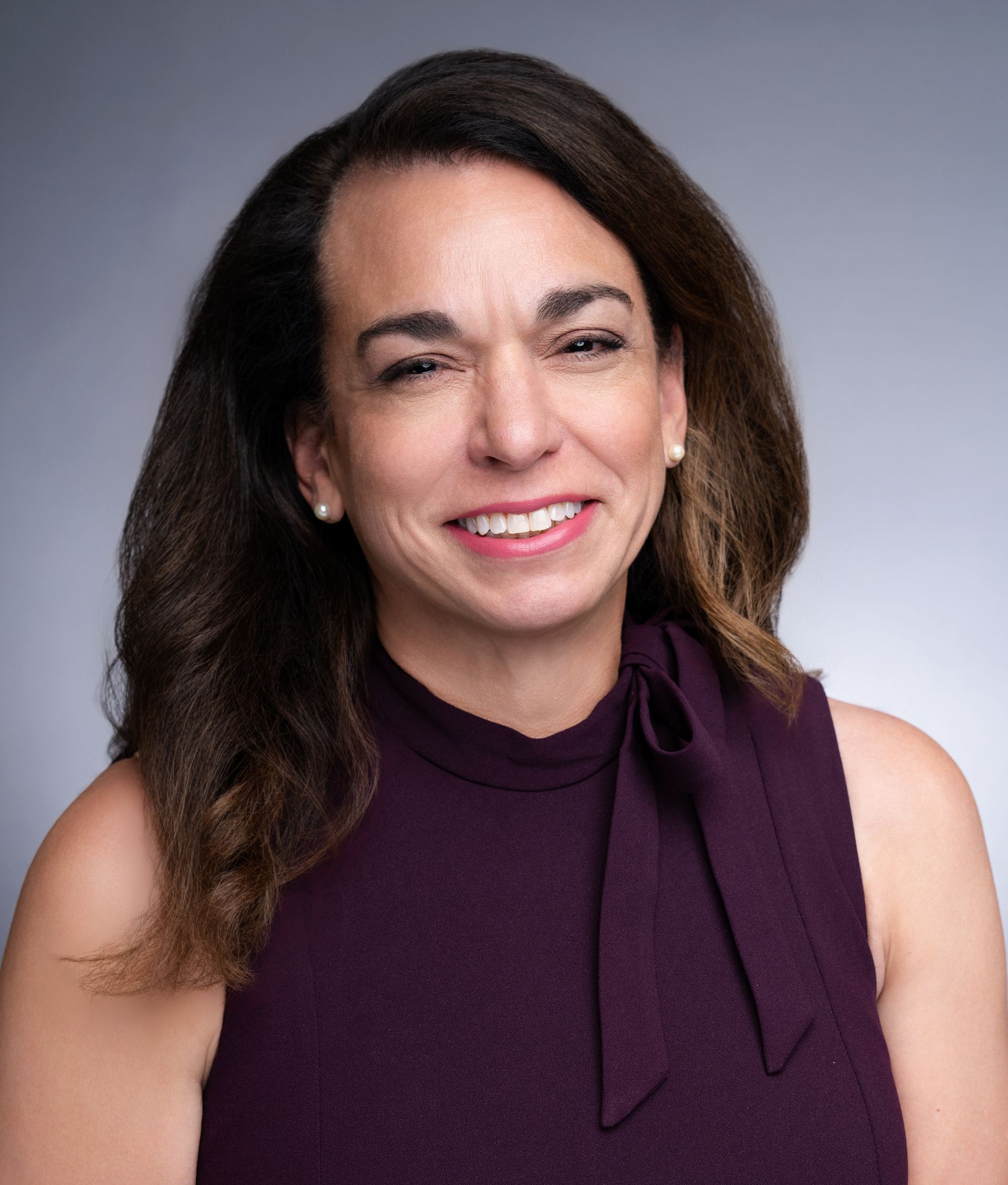 A woman in a purple dress is smiling for the camera.