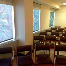 A row of chairs in a room with stained glass windows.