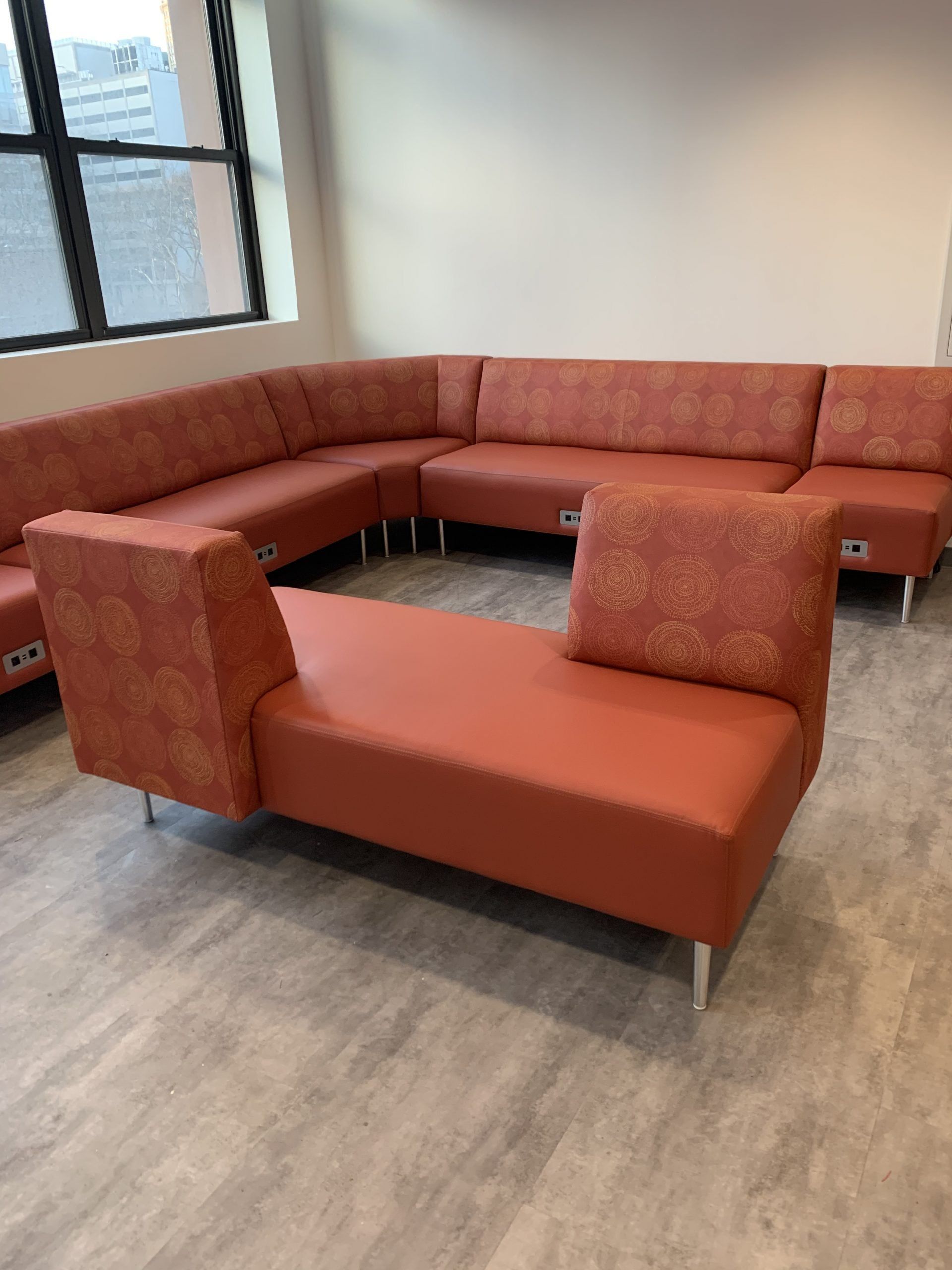 A room with a lot of red couches and chairs